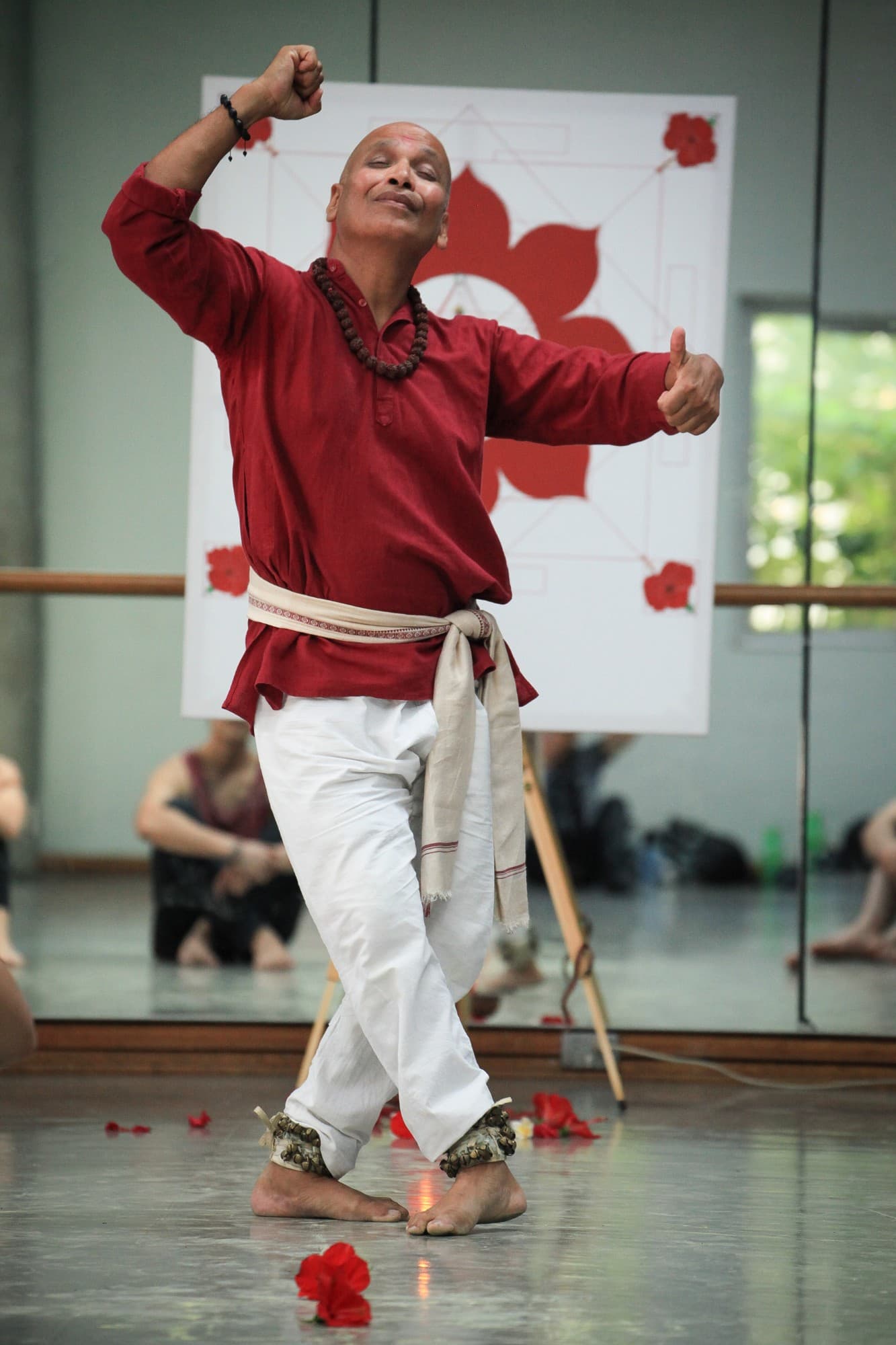 Nirmal Jena dancing Odissi at the National Institute of Dramatic Art in Sydney, with ankle bells and red hibiscus flowers on the floor, photo by Rudolf Rindler